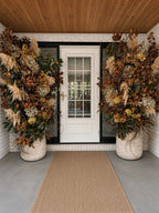 Elegant Entryway: tall dried arrangements in stone planters framing a white front door