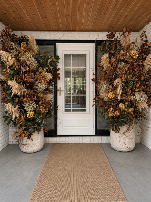 Elegant Entryway: tall dried arrangements in stone planters framing a white front door